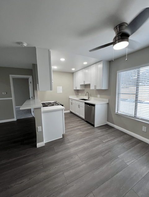 A kitchen with a white counter top and a ceiling fan.